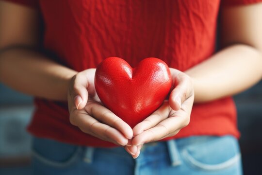 A woman holding a red heart in her hands. This image can be used to symbolize love, affection, or Valentine's Day