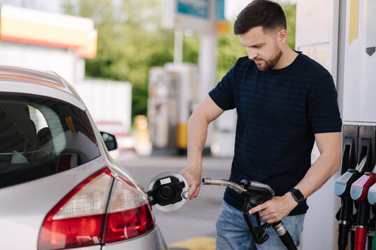 Handsome bearded man refueling car at self service gas station. Petrol concept