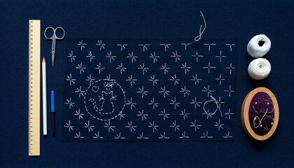Process of hand embroidery in Sashiko style on blue canvas with white threads of geometric...
