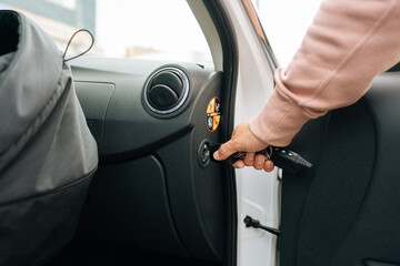 Close-up cropped shot of unrecognizable young woman turns off passenger airbag using key for...