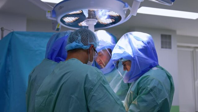 Team of professional surgeons surrounded the operational table. Doctors cooperate at trauma surgery.