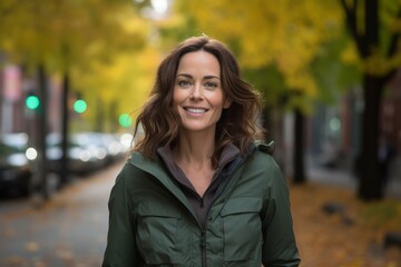 Stylish woman in a green lightweight jacket strolling through a lively city street surrounded by autumn colors