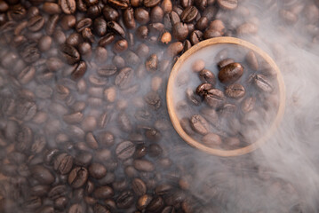 Top view of smoky roasted coffee beans in a small wooden bowl. Concept for commercial product