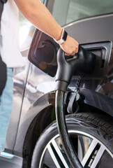 Female hand charging electric car.