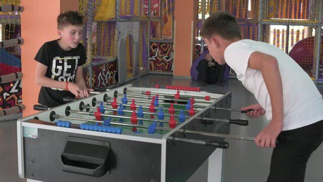 Two boys are playing table football in the playroom