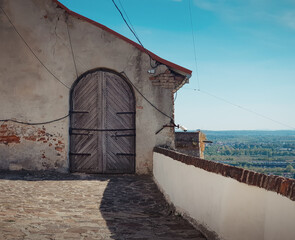 Old wooden door in a house wall on top of the hill. Terrace of high castle overlooking  hilly rural...