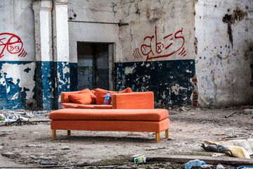 Pomarańczowa kanapa w starej zrujnowanej fabryce