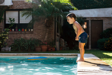 Little boy jumping in a pool. Child get fun in the swimming pool of his home.