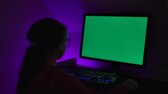 Girl of Green Screen Display PC at Desk in Home at Night. Desktop PC Monitor With Green Mockup, Chroma Key, Working. Person Teenager Programer Typing Codes Mockup Computer. Software Development.