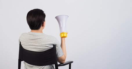 Man sitting on black director chair. He holding a megaphone on white background.
