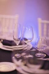Luxury Table setting focus on the glass blue and purple background. Empty glasses set in restaurant.