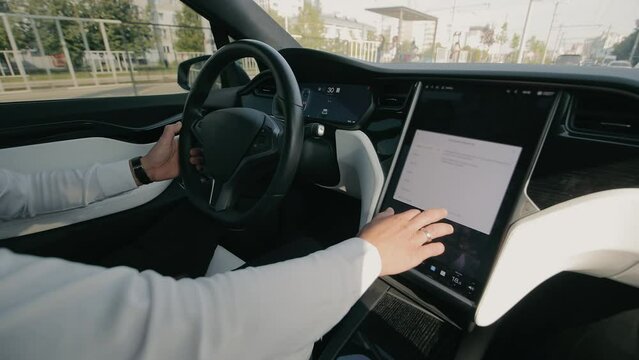 Driver in Modern Electric Vehicle, Man in a white shirt operating a touchscreen dashboard in a high-tech electric car interior