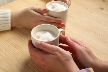 Women having coffee break at light wooden table, closeup