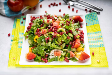 Pomegranate Salad with strawberry, cucumber, tomato, cauliflower and green leaves served in dish isolated on table top view of arabic food