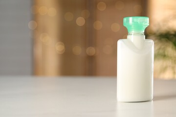Mini bottle of cosmetic product on white table against blurred background. Space for text