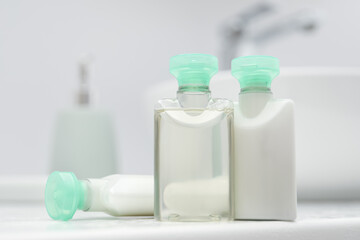 Mini bottles of cosmetic products on white countertop in bathroom, closeup