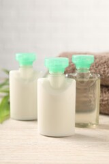 Mini bottles of cosmetic products on white wooden table