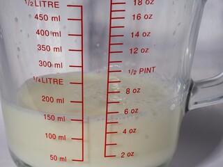 Jug of milk in glass measuring jug white background 