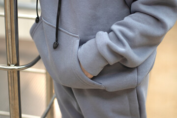 young woman in gray hoodie hands in the pockets close up mockup copyspace. High quality photo. Long warm sleeve and patch pocket. Clothing for autumn or winter. High quality photo