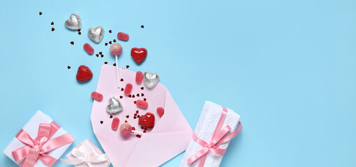 Tasty candies with envelope and gifts on blue background with space for text. Valentine's Day...