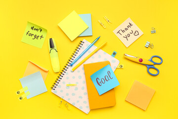 Sticky notes with notebooks and stationery on yellow background