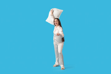 Pretty young woman with soft pillow on blue background