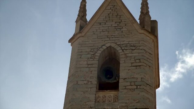 Slow motion, bells ringing in the bell tower, blue sky with clouds.