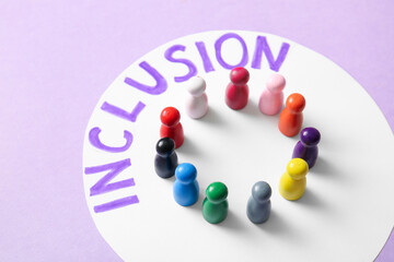 Paper with word INCLUSION and pawns on lilac background, closeup