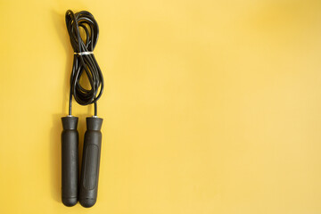 Skipping rope with black handles on the yellow background. 