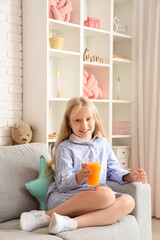 Little girl with glass of juice at home