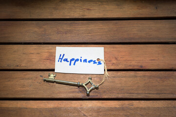 old key with the word happiness written on a tag on a wooden background