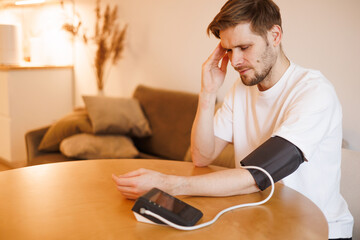 A male monitors his blood pressure in the comfort of his home, focusing on men's health and...