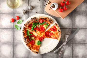 Plate with slices of tasty pizza Margarita, spices and fresh tomatoes on grey tile background
