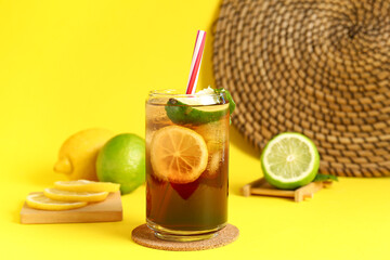 Glass of cold Long Island iced tea on yellow background