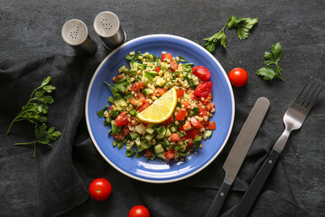 Plate with delicious tabbouleh salad on dark background