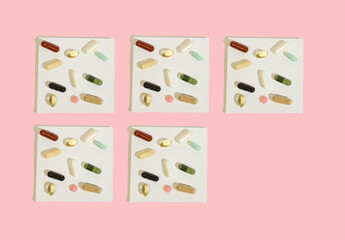 Pills and supplements on a white and pink background. Minimal medical concept.Copy space. Flat lay. 