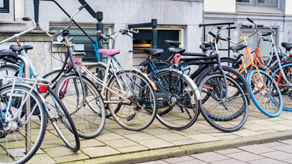 Fototapeta na wymiar Bicycle parking in the city. An urban cityscape with bicycles. Bicycle parking along a street in Amsterdam. Old walking bikes parked carelessly outside an old city building in Netherlands.