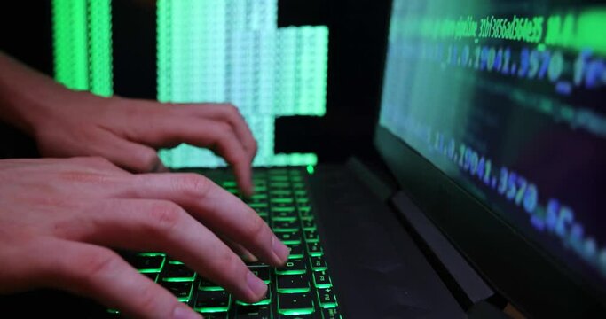 Close up of hands typing code on a laptop keyboard with multiple screens of codes and program software. Hacking or programming concept