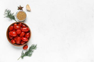 Bowl of pickled tomatoes and different spices on white background
