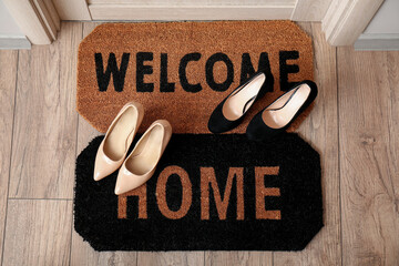 Doormats with words and shoes in hall, top view