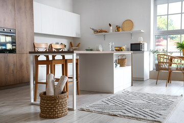 Interior of modern kitchen with white furniture and wooden island table