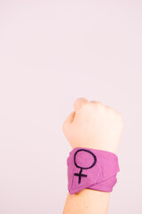 Feminism concept. Girl raising her fist with a lilac bracelet.