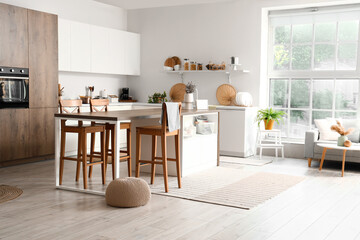 Interior of modern kitchen with white furniture and island table