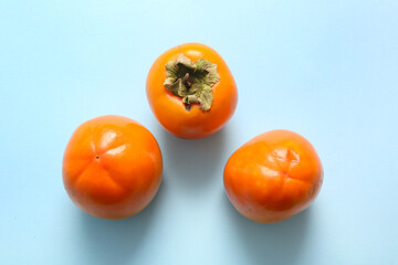 Sweet ripe persimmons on blue background