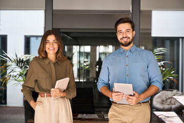 Two business partners executives standing in office looking at camera. 2 sales managers, company...