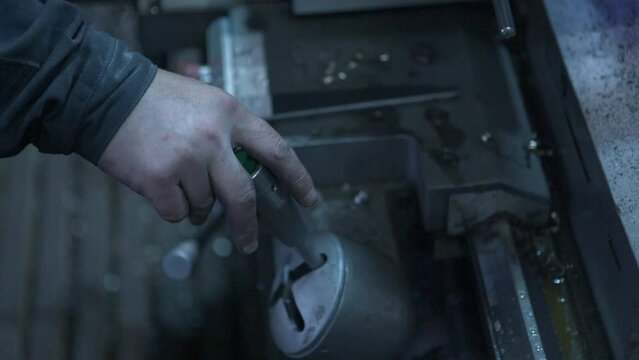 A worker's hand pulls a lever on a machine at the factory