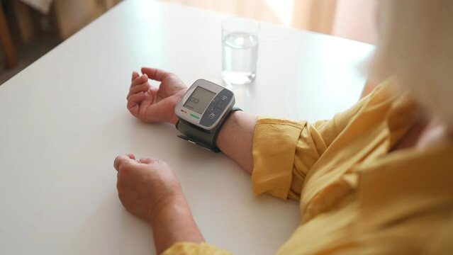 Senior woman is checking blood pressure and heart rate with digital pressure gauge by herself at home.Older woman taking care for health. Health and Medical concept. High quality FullHD footage