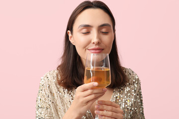 Beautiful young woman with glass of wine on pink background