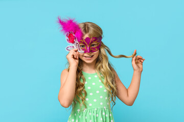 Funny little girl wearing carnival mask on blue background