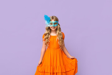 Happy little girl wearing carnival mask on lilac background